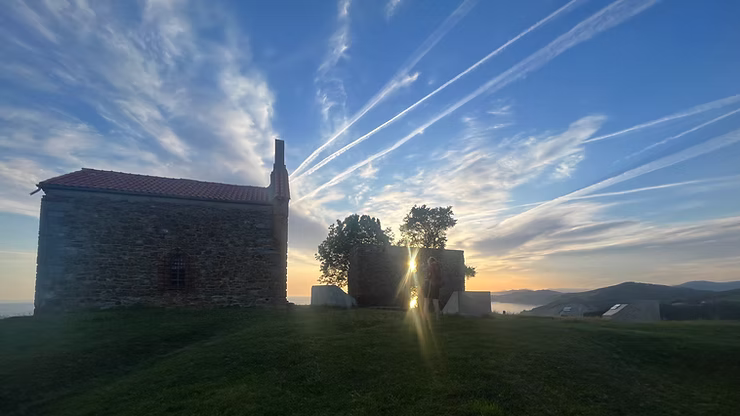 Kirche am Jakobsweg, Pilgerin bei Sonnenaufgang